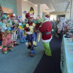 Children watch the Grinch and performers in Mario costumes high five at the Family Holiday Celebration