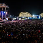 A vast audience listens to a live concert at night during the Barefoot Country Music Fest.